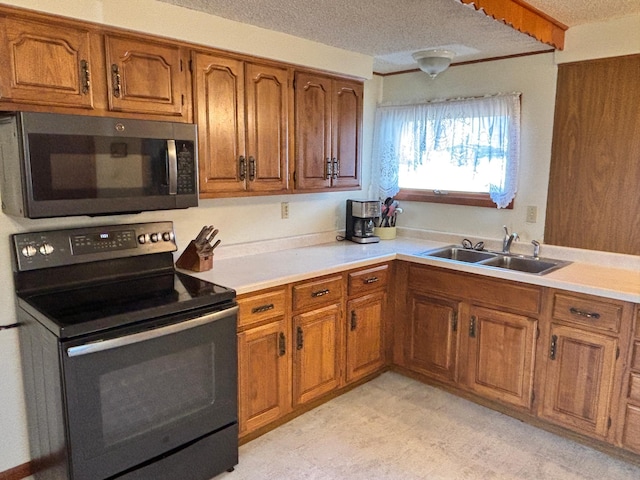 kitchen featuring brown cabinetry, light countertops, a sink, and electric range