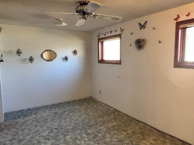 empty room with ceiling fan, carpet floors, and a textured ceiling