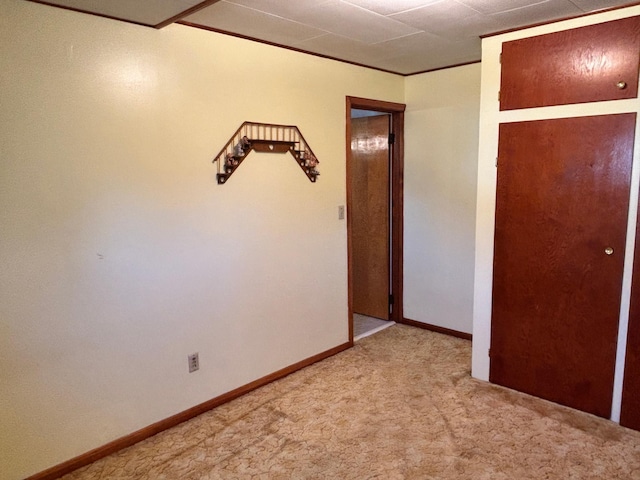 spare room featuring light carpet, baseboards, and ornamental molding