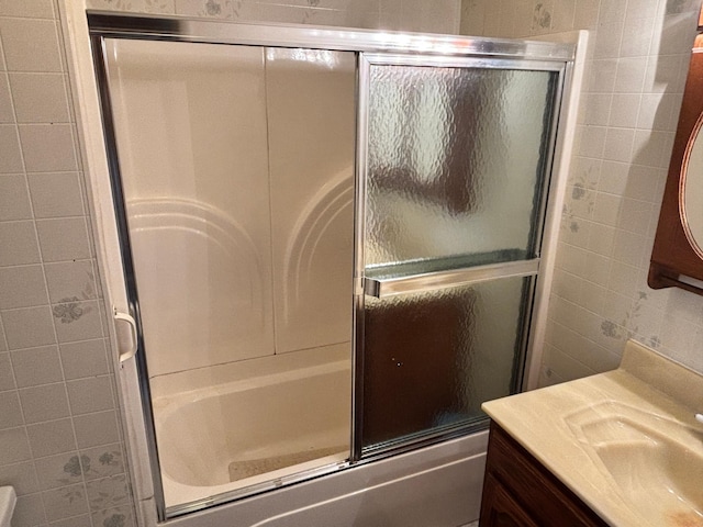 bathroom with combined bath / shower with glass door, tile walls, and vanity