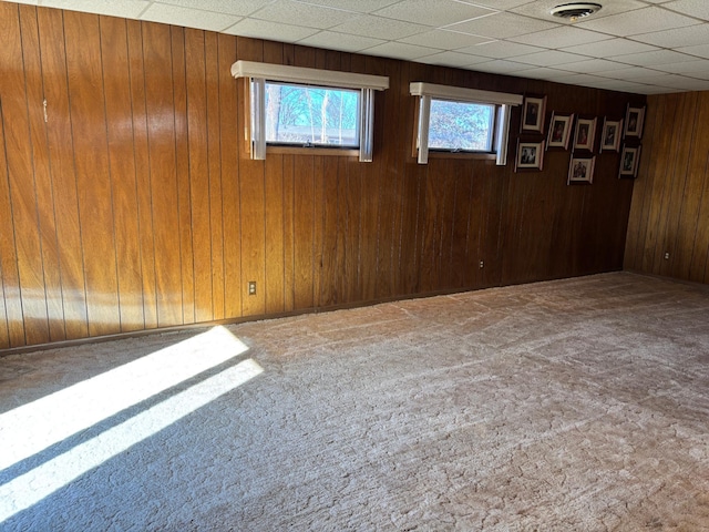 spare room with carpet floors, a paneled ceiling, visible vents, and wooden walls