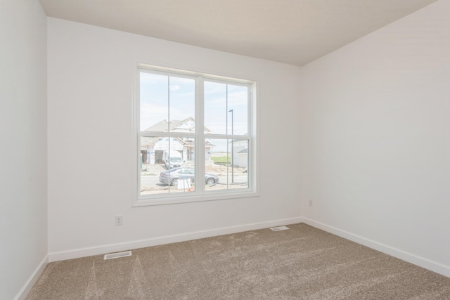 carpeted spare room with visible vents and baseboards