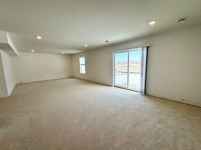 spare room featuring recessed lighting, light carpet, visible vents, and a textured ceiling