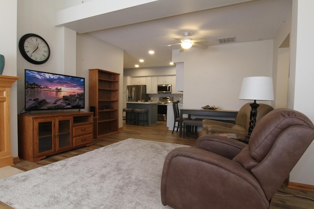 living area featuring light wood-style floors, ceiling fan, and visible vents