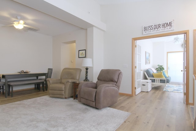 living area with light wood-style floors, visible vents, ceiling fan, and baseboards