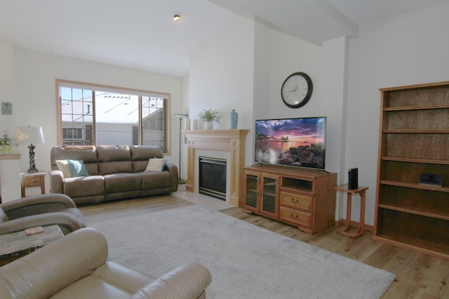 living area featuring light wood-type flooring, a fireplace with flush hearth, baseboards, and vaulted ceiling