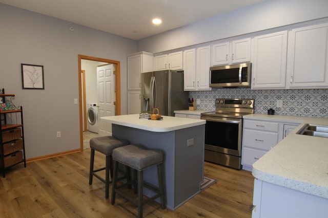 kitchen with light countertops, appliances with stainless steel finishes, washer / clothes dryer, and white cabinetry