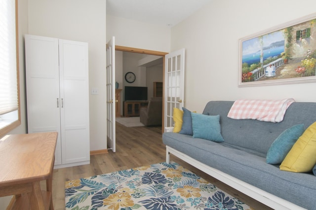 living area with light wood-type flooring, baseboards, and french doors