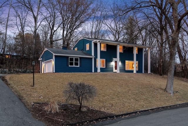 view of front facade featuring a front lawn, a garage, and a chimney