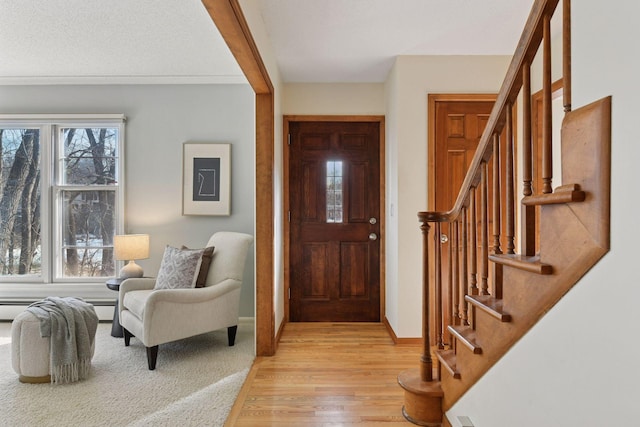 entrance foyer with stairway, baseboards, light wood-style floors, and a healthy amount of sunlight