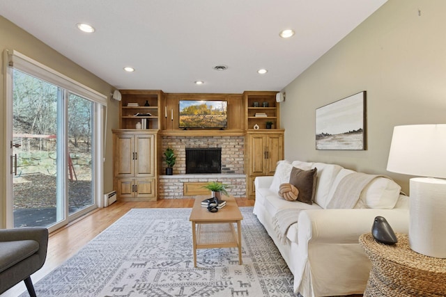 living area with light wood finished floors, visible vents, a brick fireplace, recessed lighting, and a baseboard radiator