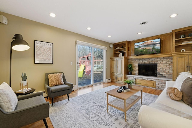 living room featuring light wood-style flooring, recessed lighting, a fireplace, and visible vents