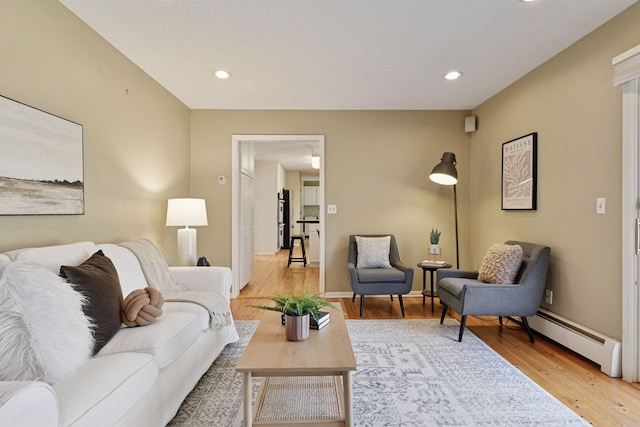 living area with recessed lighting, a baseboard radiator, and light wood finished floors