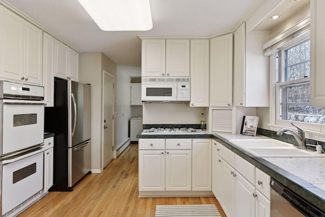 kitchen with a sink, stainless steel appliances, white cabinets, and a baseboard radiator