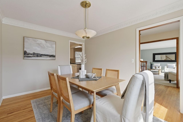 dining area featuring light wood-style floors, baseboards, and ornamental molding