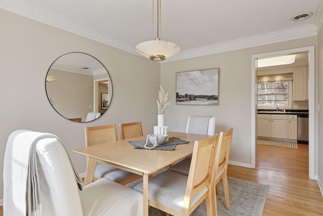 dining room featuring visible vents, baseboards, ornamental molding, and light wood finished floors