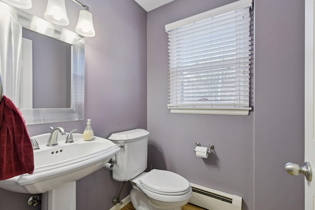 half bath featuring a baseboard heating unit, toilet, baseboards, and a sink