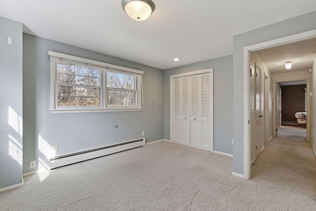 unfurnished bedroom featuring carpet flooring, baseboards, a closet, and a baseboard radiator