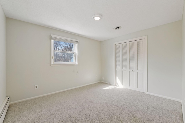 unfurnished bedroom featuring visible vents, a baseboard heating unit, baseboards, carpet floors, and a closet