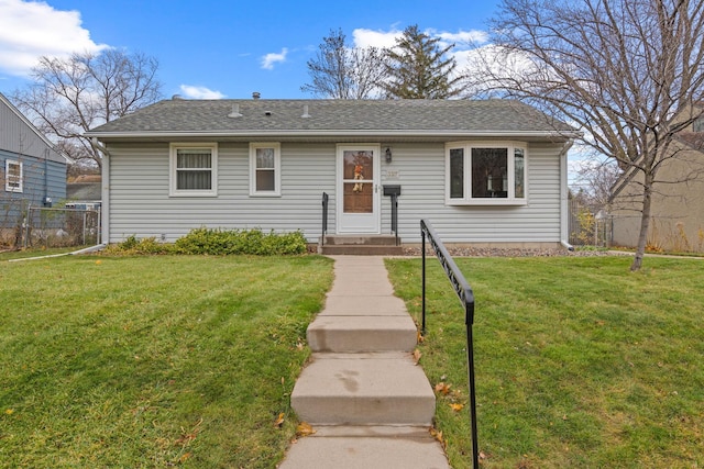 view of front facade with a front yard, fence, and entry steps