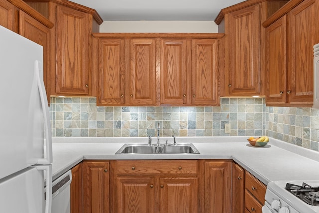 kitchen featuring white appliances, tasteful backsplash, light countertops, and a sink