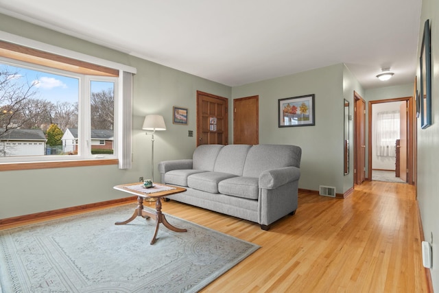 living area featuring light wood finished floors, plenty of natural light, visible vents, and baseboards