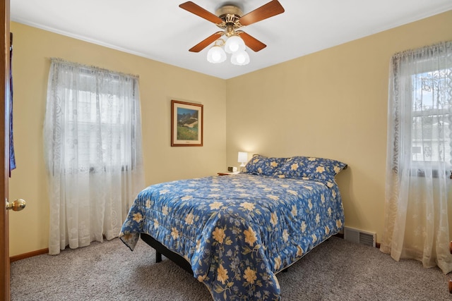 carpeted bedroom featuring a ceiling fan, visible vents, and baseboards