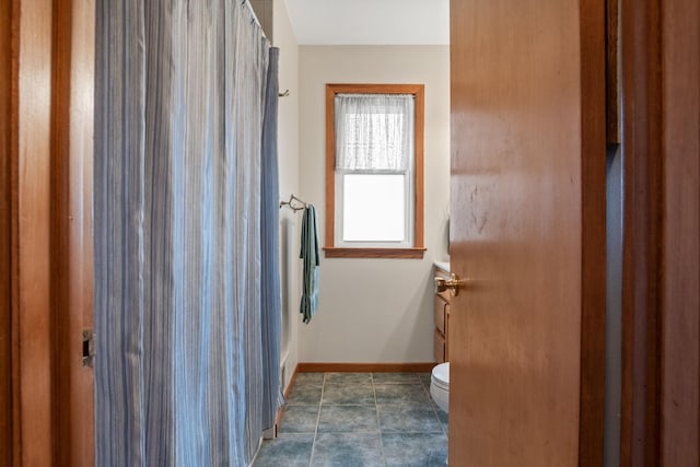 bathroom featuring curtained shower, tile patterned flooring, toilet, and baseboards