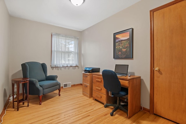 office space featuring baseboards, visible vents, and light wood finished floors