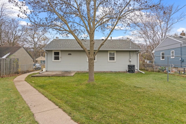 back of property with a patio area, a fenced backyard, a shingled roof, and a lawn