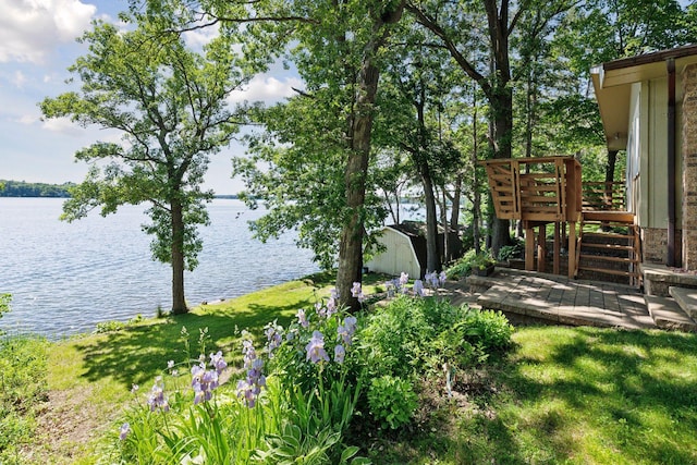 view of yard featuring a shed, a water view, and an outdoor structure