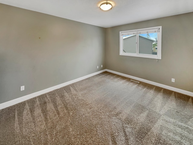 unfurnished room with carpet, visible vents, and baseboards