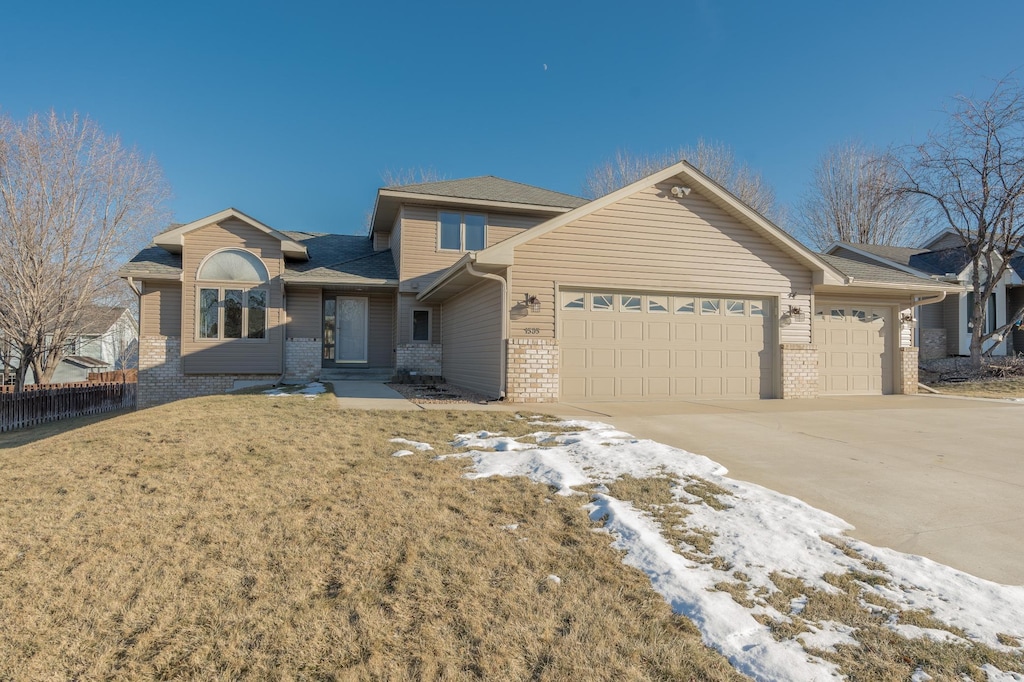 view of front of property featuring a garage, driveway, fence, and brick siding