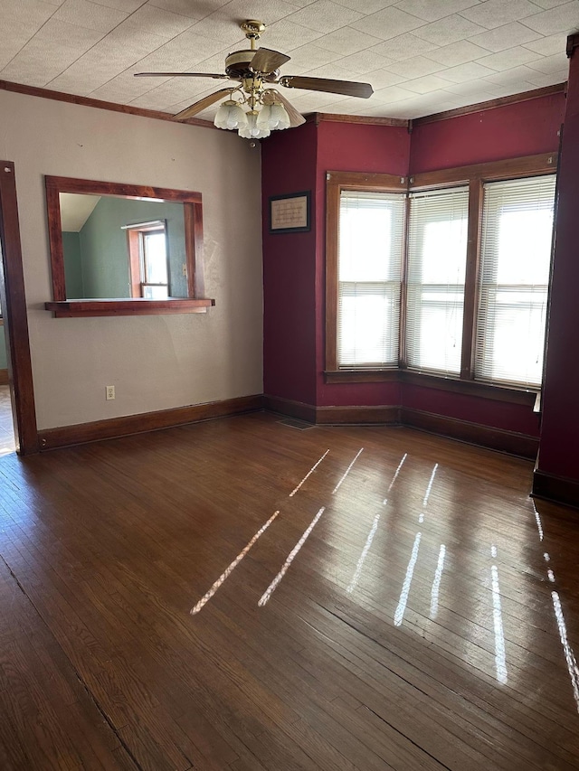 unfurnished room with dark wood-type flooring, ornamental molding, baseboards, and a ceiling fan