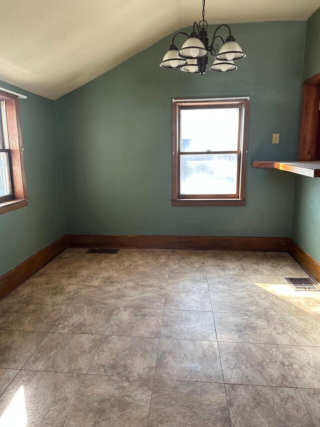 spare room with a notable chandelier, vaulted ceiling, visible vents, and baseboards