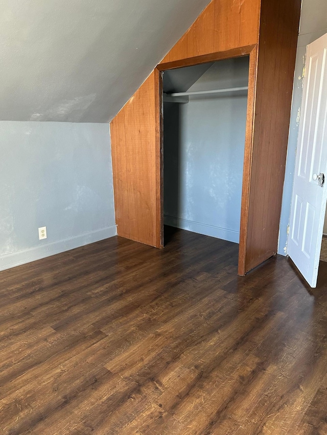 bonus room with wood walls, baseboards, vaulted ceiling, and dark wood-style flooring