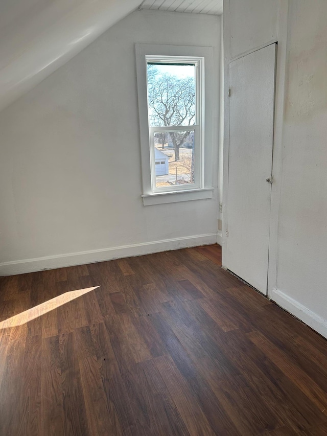 additional living space with baseboards, vaulted ceiling, and dark wood-style flooring