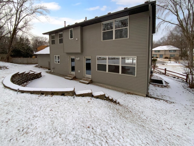 snow covered rear of property with entry steps and fence