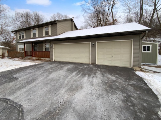 view of front facade featuring a garage, covered porch, and aphalt driveway