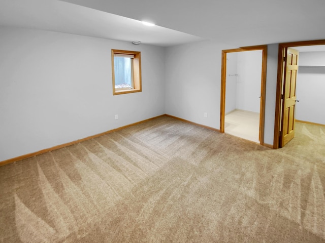 unfurnished bedroom featuring a closet, baseboards, a walk in closet, and carpet flooring