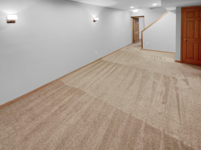 finished below grade area featuring baseboards, recessed lighting, and light colored carpet