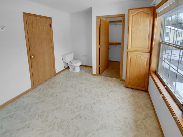 unfurnished bedroom featuring a spacious closet, baseboards, and a closet