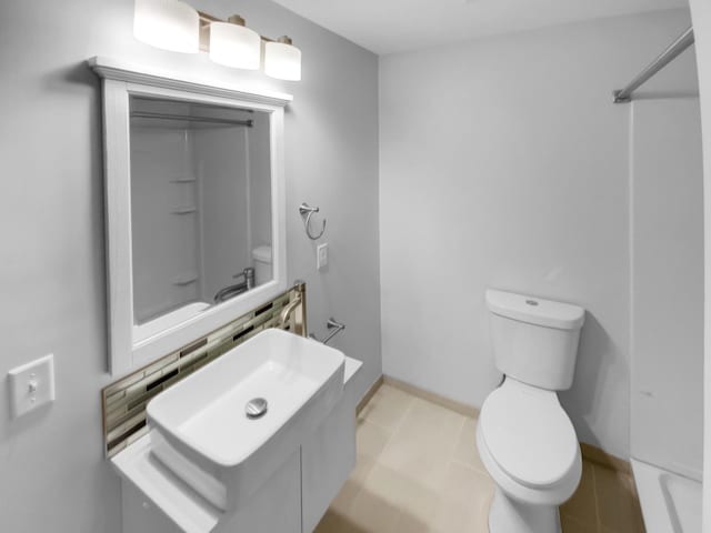 full bathroom featuring decorative backsplash, vanity, toilet, and tile patterned floors