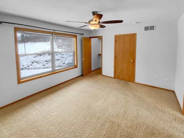 unfurnished bedroom featuring light colored carpet, visible vents, ceiling fan, and baseboards