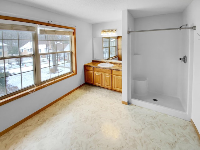 full bath with baseboards, tile patterned floors, walk in shower, a textured ceiling, and vanity