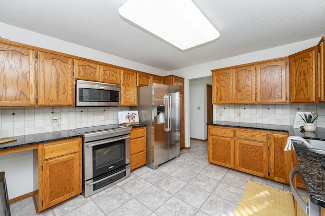 kitchen featuring decorative backsplash, brown cabinets, appliances with stainless steel finishes, and a textured ceiling