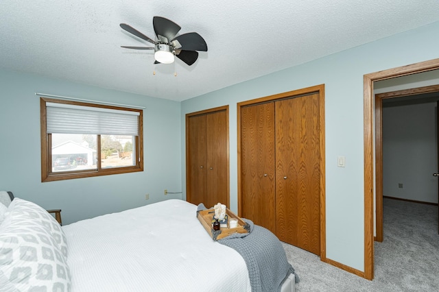 bedroom with carpet flooring, baseboards, multiple closets, and a textured ceiling