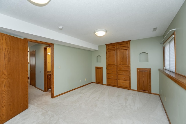 unfurnished bedroom featuring baseboards, light colored carpet, and a textured ceiling