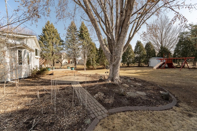 view of yard with an outbuilding, a playground, and a storage unit