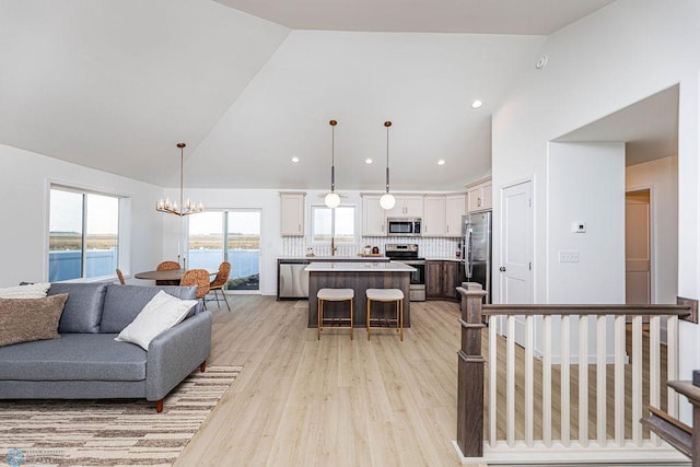 living area with high vaulted ceiling, a chandelier, and light wood-style floors